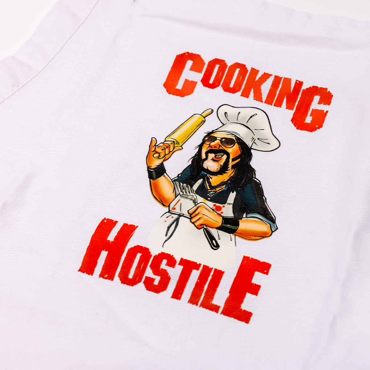 T-shirt with a graphic of a chef holding a rolling pin and text 'Cooking Hostile' on a white background